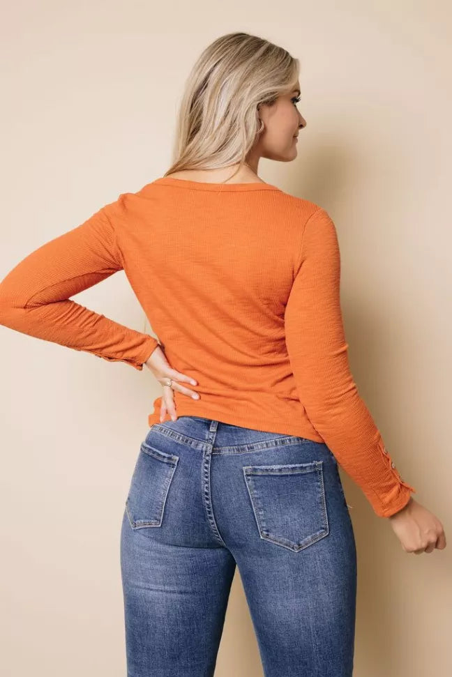 Rust brown long-sleeve henley top shown from the back with curved hem