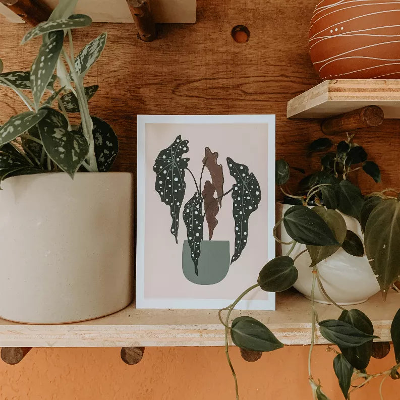 Framed botanical print featuring dark green polka-dot leaves and a beige potted plant