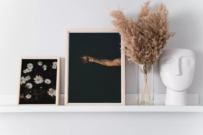 Small light-framed daisy floral art print with white petals and yellow centers on dark background.