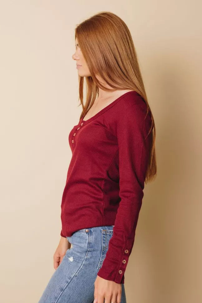 Burgundy long-sleeve button top, side view showing cuff buttons and neckline placket
