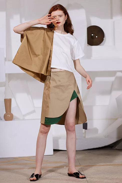 Rimless beige high front open slit skirt with green underlayer visible at the slit