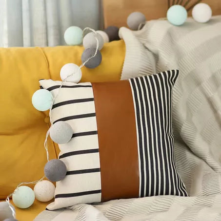 Throw pillow cover with black-and-white stripes, brown center panel, and pom-pom trim