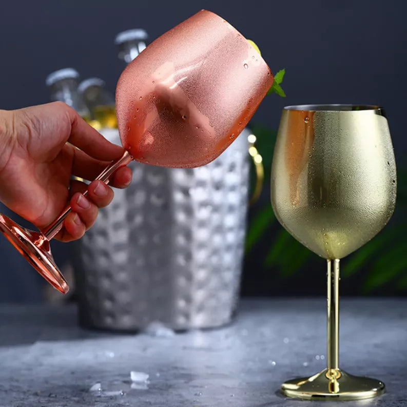 Hand holding a tilted rose-gold cocktail glass with lemon wedge; mirrored finish
