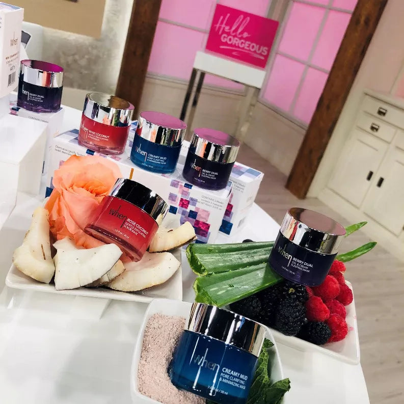 Mini cream mask jars in blue, purple, and red displayed on a tray with fruit