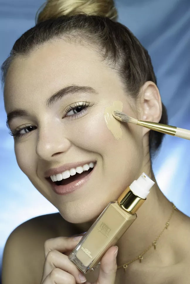 Liquid foundation bottle with dropper and makeup brush applying product to face