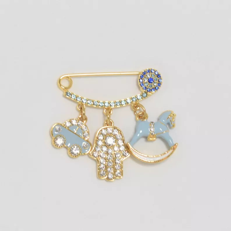 Gold-tone baby safety pin with blue rhinestone head and three dangling charm shapes