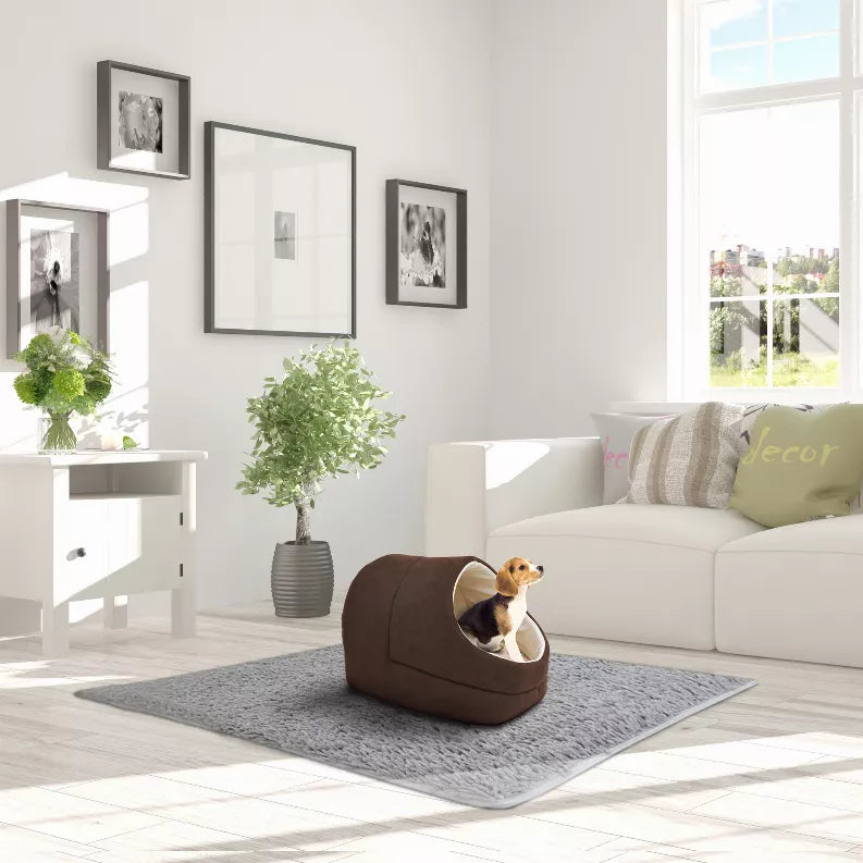 Brown cat cave bed with oval entrance and light lining, orange cat inside on rug