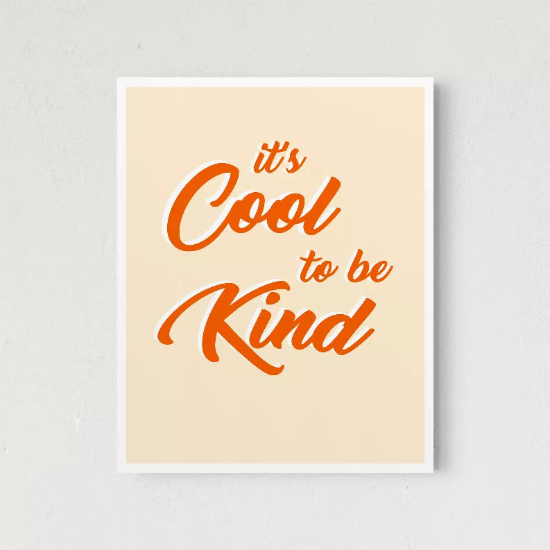 Framed wall art with orange script quote "It's Cool to be Kind" on light cream background