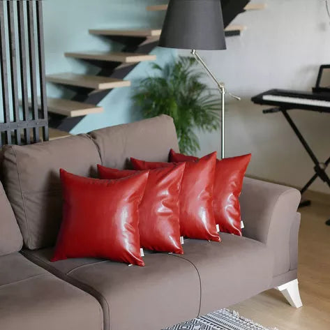 Red faux leather throw pillows on a gray sofa, glossy look, square shape