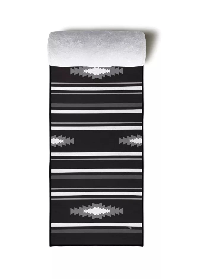 Black yoga towel with horizontal stripes and zigzag motifs, gray rolled top