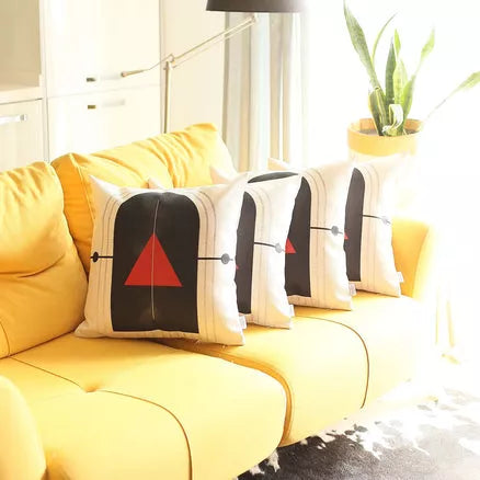 Throw pillow covers on sofa: white with black arch and red tree, plus striped accents