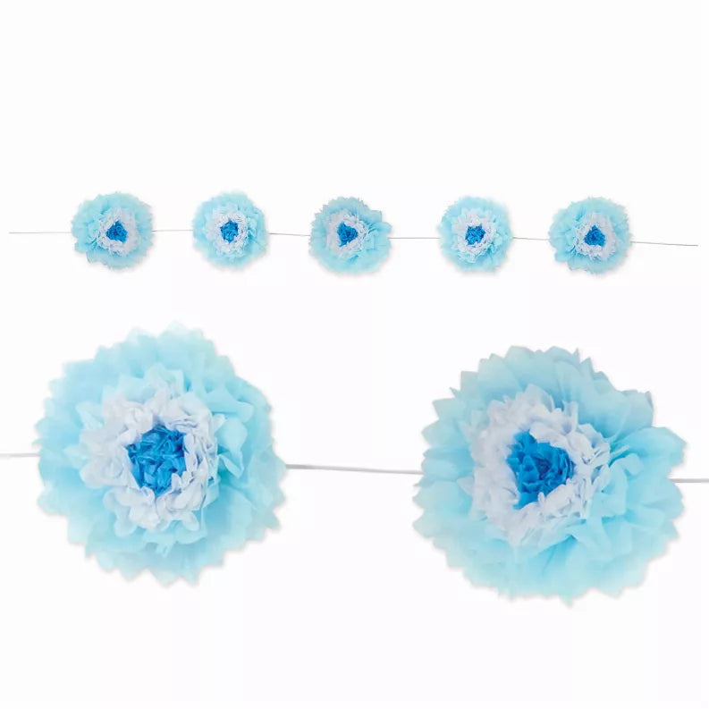 Blue tissue pom-pom decorations on a string, with layered flower-like petals.