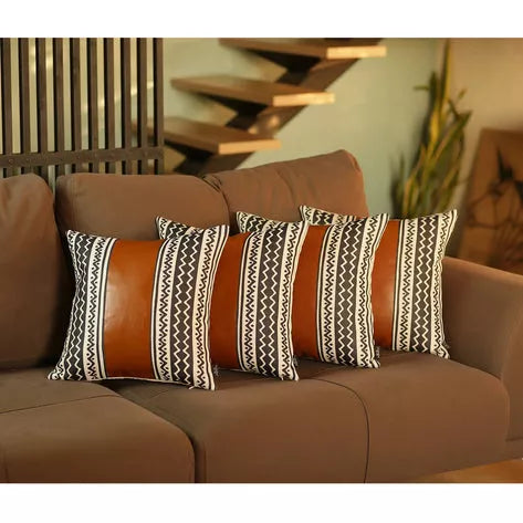 Set of black-and-white zigzag striped throw pillows with solid tan backs on sofa