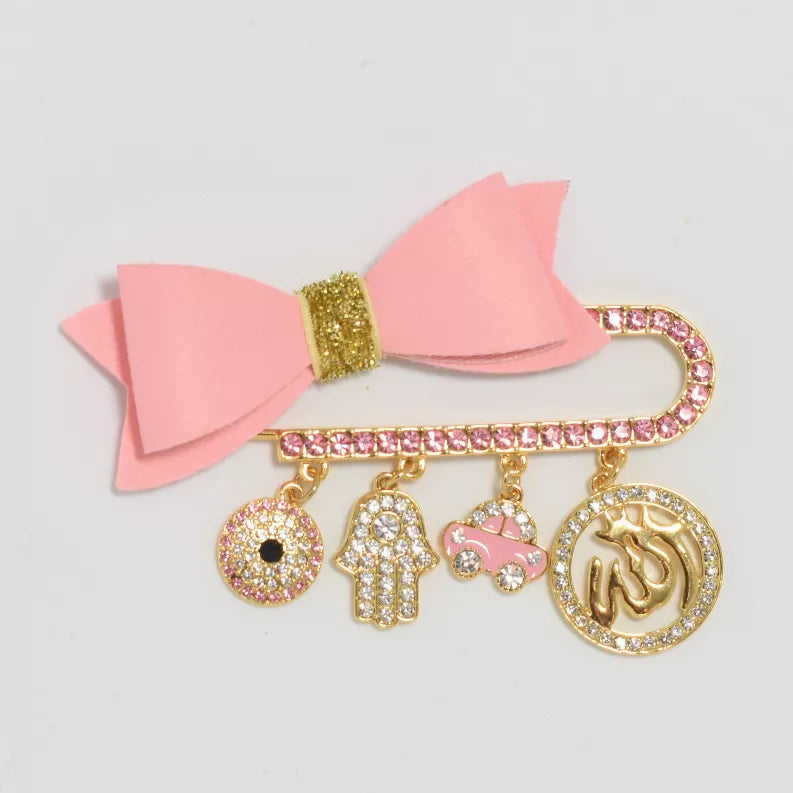 Pink bow baby safety pin with glitter charms: heart, hamsa, hand, donut, bell