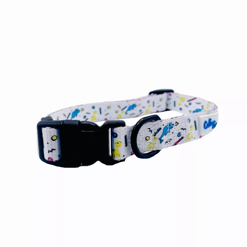 Dog collar end view, light gray strap with black hardware and colorful dinosaur confetti pattern