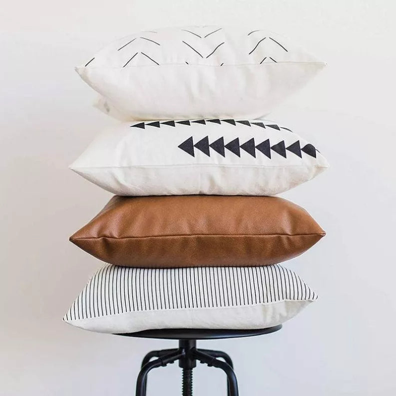 Set of 4 faux leather throw pillow covers shown stacked: white with black icons, brown, striped
