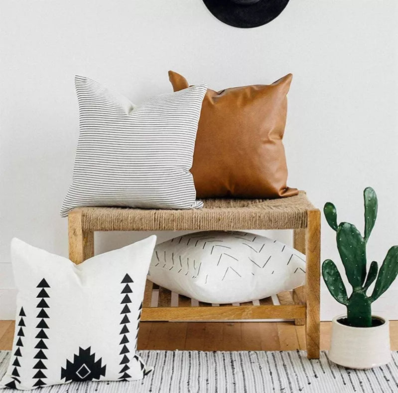 Four faux leather throw pillow covers with black-and-white geometric prints and brown leather-look