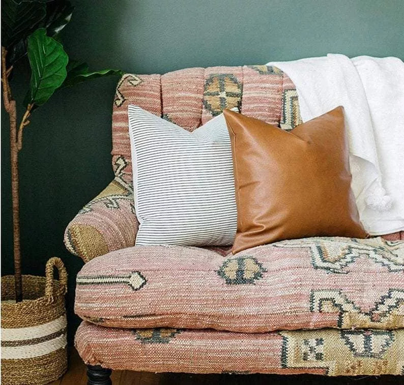 Four faux leather throw pillow covers on sofa: striped, brown leather-look, and patterned white