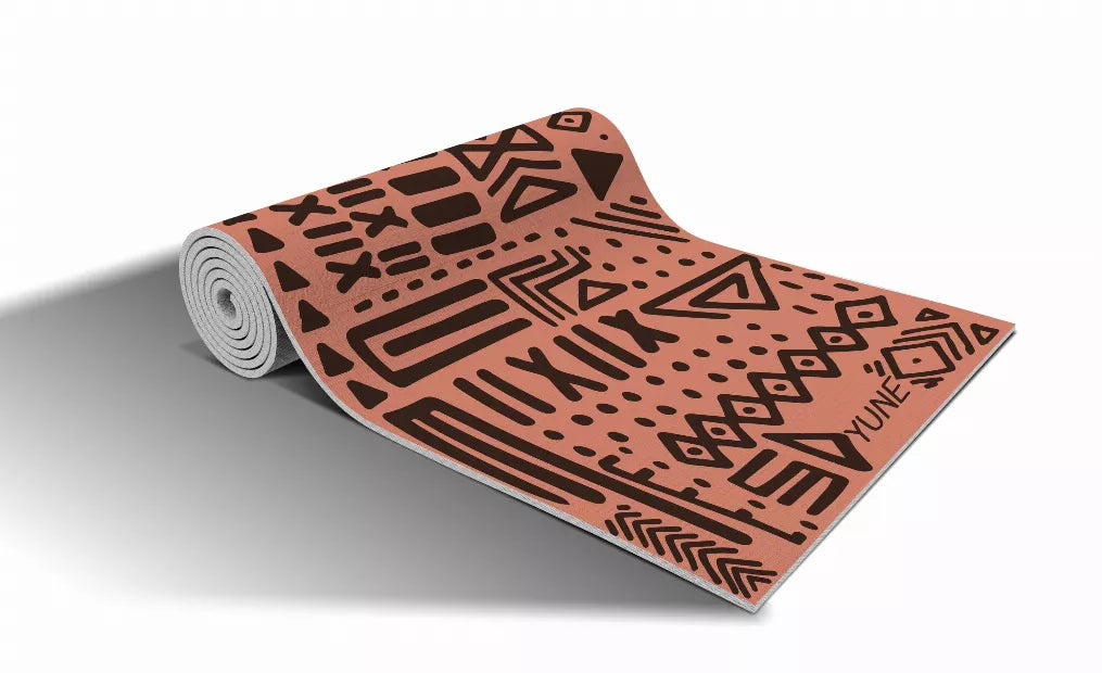 Rolled yoga mat with terracotta and black patterned surface, angled view