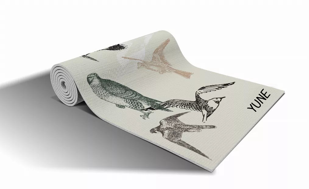 Light beige yoga mat with bird and animal illustration pattern, rolled up