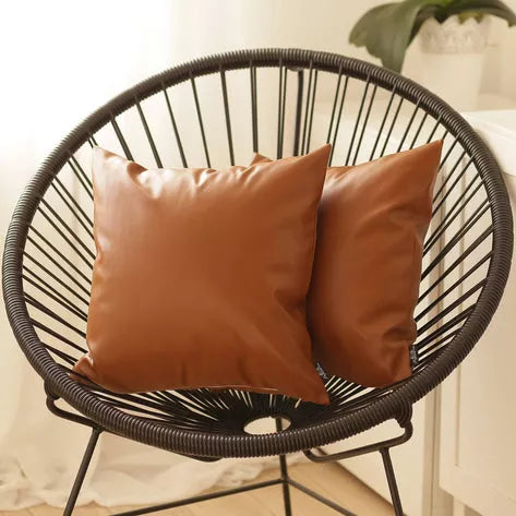 Pair of brown faux leather throw pillows with smooth fabric and square shape