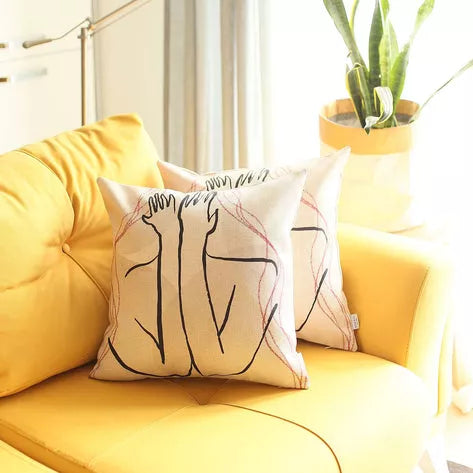Printed throw pillow cover on a yellow sofa, white with black and red line-art faces
