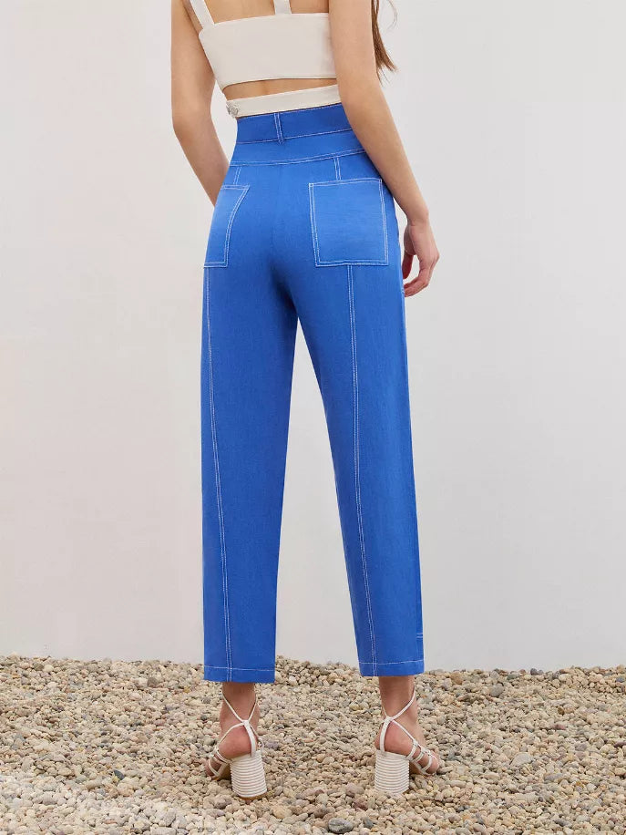 Blue linen carrot pants on model, side view with contrast stitched pockets and hem detail