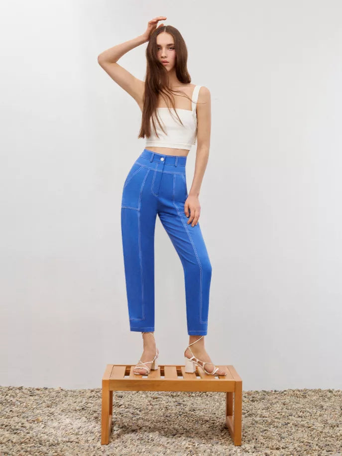 Blue linen carrot pants with front button closure and contrast stitching, worn with sandals
