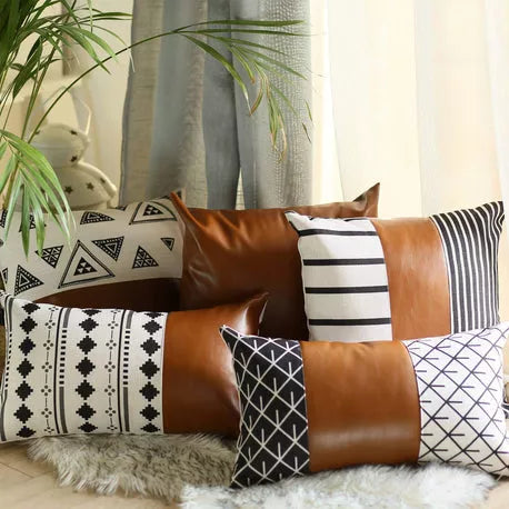 Brown faux leather throw pillow with white geometric and black stripe accent pillows on sofa