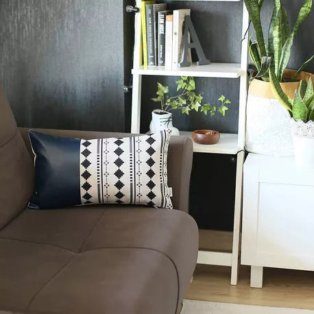Black and white patterned faux leather pillow on dark sofa, styled with geometric accents