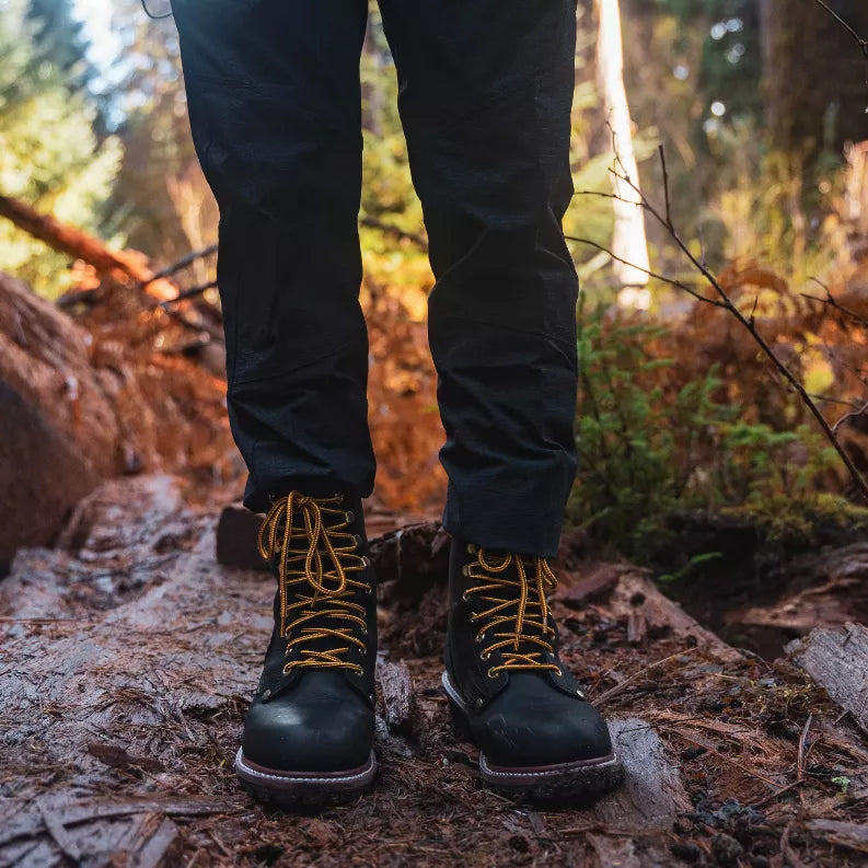 Waterproof steel toe logger boots worn outdoors with dark pants on rocks