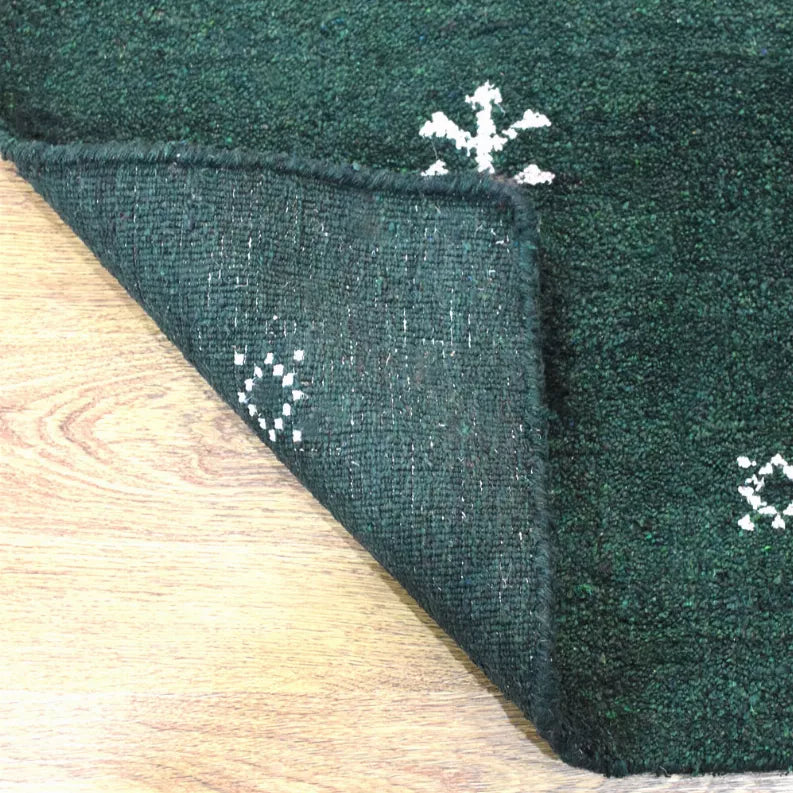 Green rug edge and corner with visible texture and white motif print