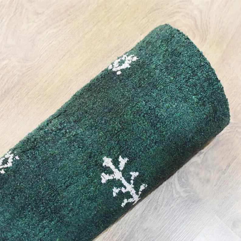 Green rug corner with white branch-like motif on textured pile