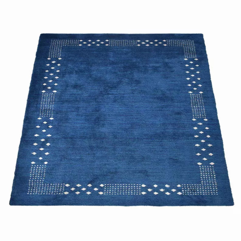 Blue square area rug with a white dotted border and central geometric pattern.