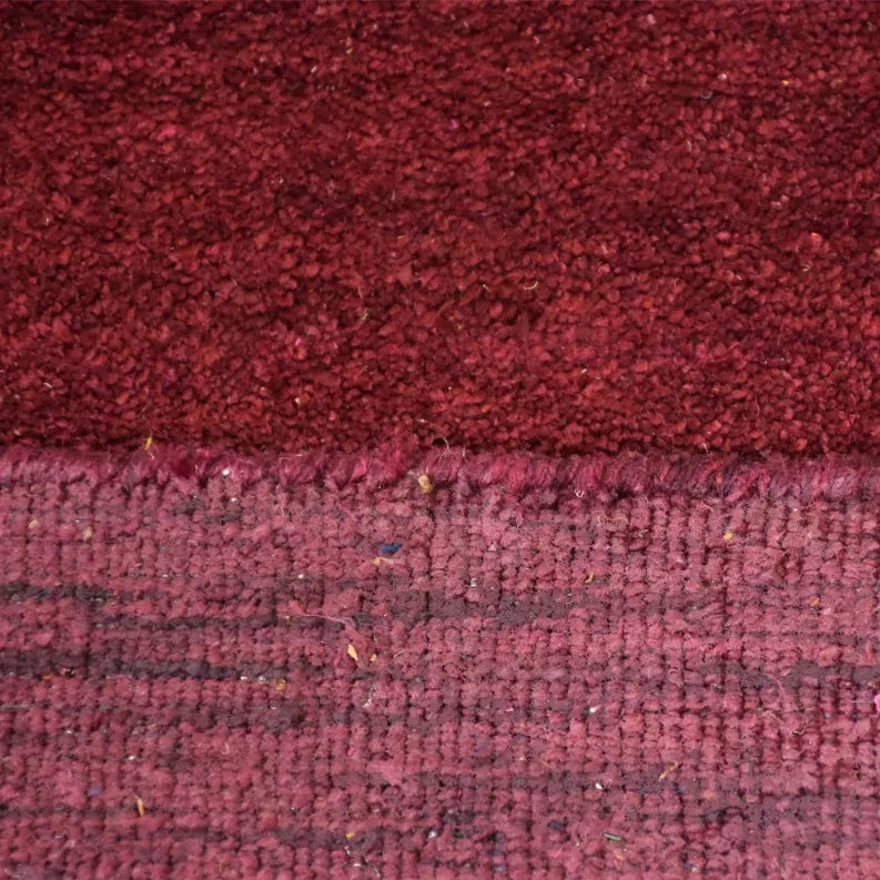 Close-up of burgundy hand-knotted rug pile and weave texture