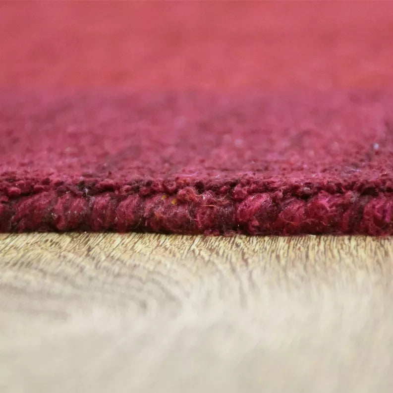 Maroon rug pile close-up with dense texture and woven edge detail.