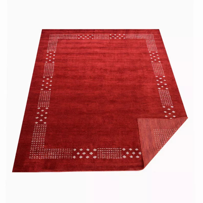 Red area rug with cream geometric border and diamond pattern accents around edges.