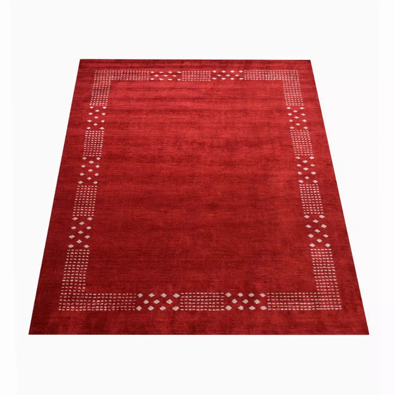 Red area rug with cream geometric corner blocks and diamond-dot border on all sides.