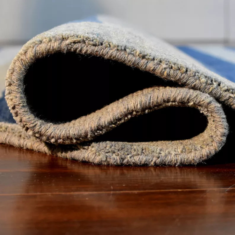 Blue and gray striped octagon area rug rolled edge view, showing short wool pile