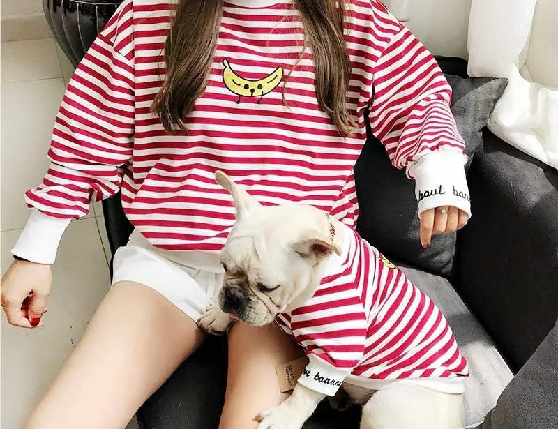 Matching pet and owner red-and-white striped T-shirts, dog lying with woman