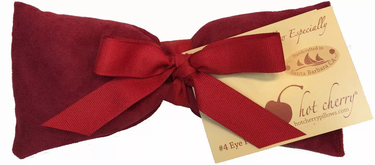 Red suede eye pillow with bow tie and hang tag labeled for therapy pillow.