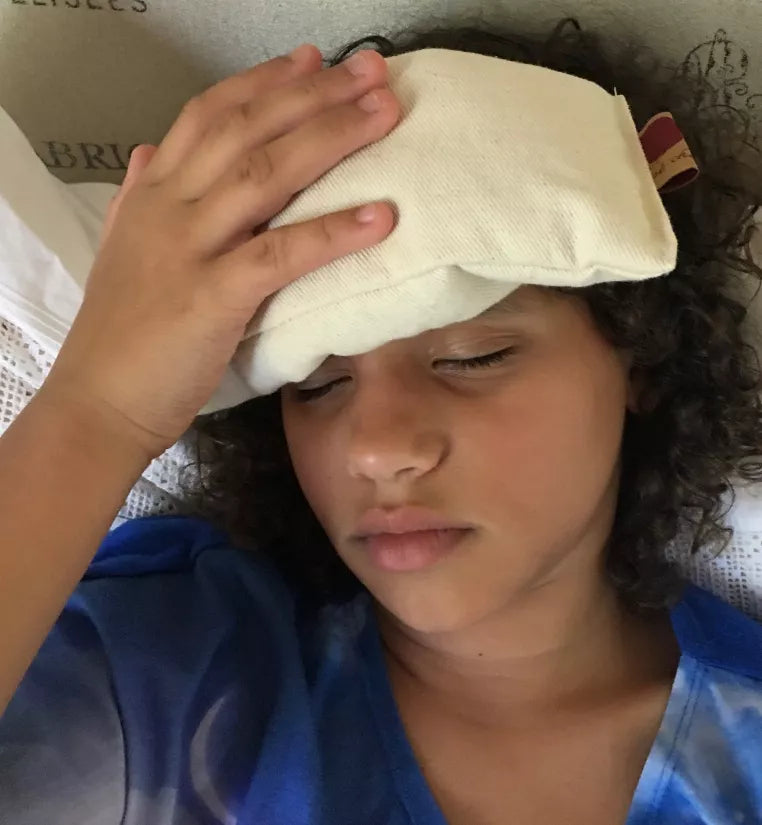 Cream eye pillow over forehead, soft fabric with corner tag