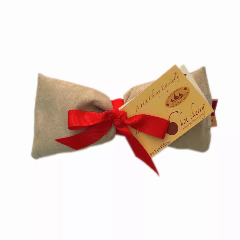 Tan eye pillow with red bow and brand tag