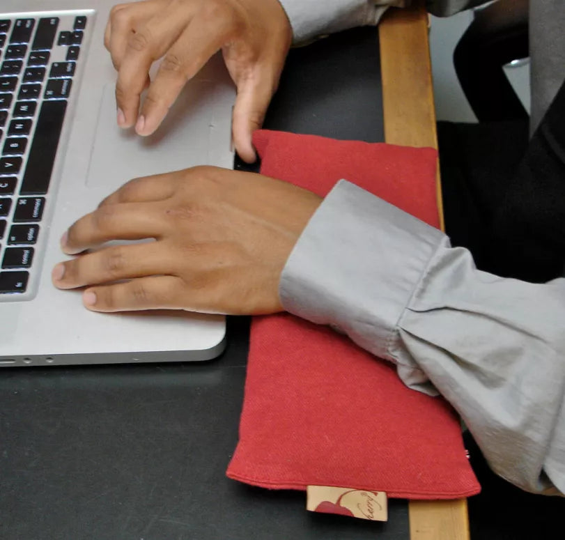 Red eye pillow folded on desk, visible fabric and corner label