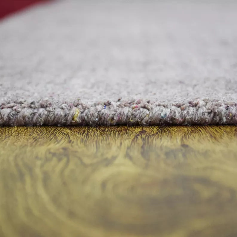 Hand-knotted area rug edge close-up with light gray, speckled textured pile