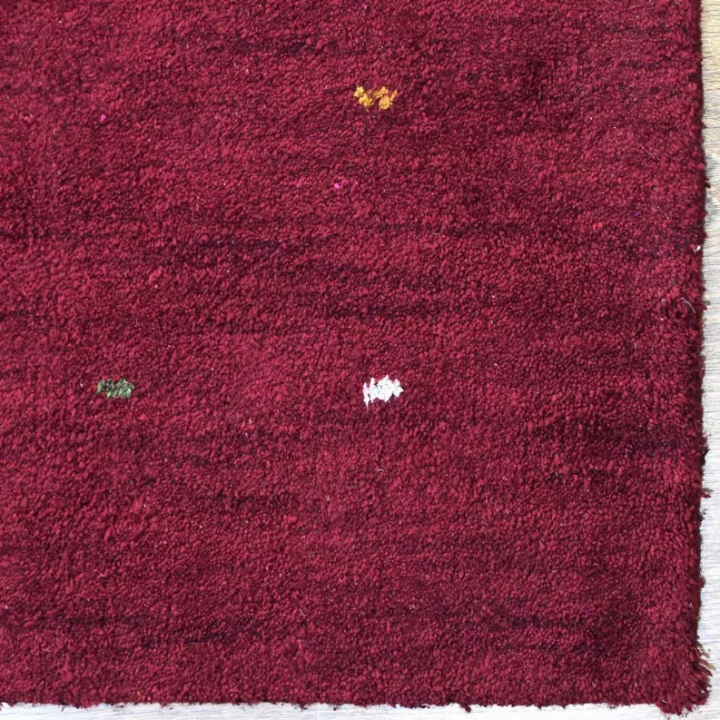 Maroon textured area rug with multicolor specks and short, dense pile