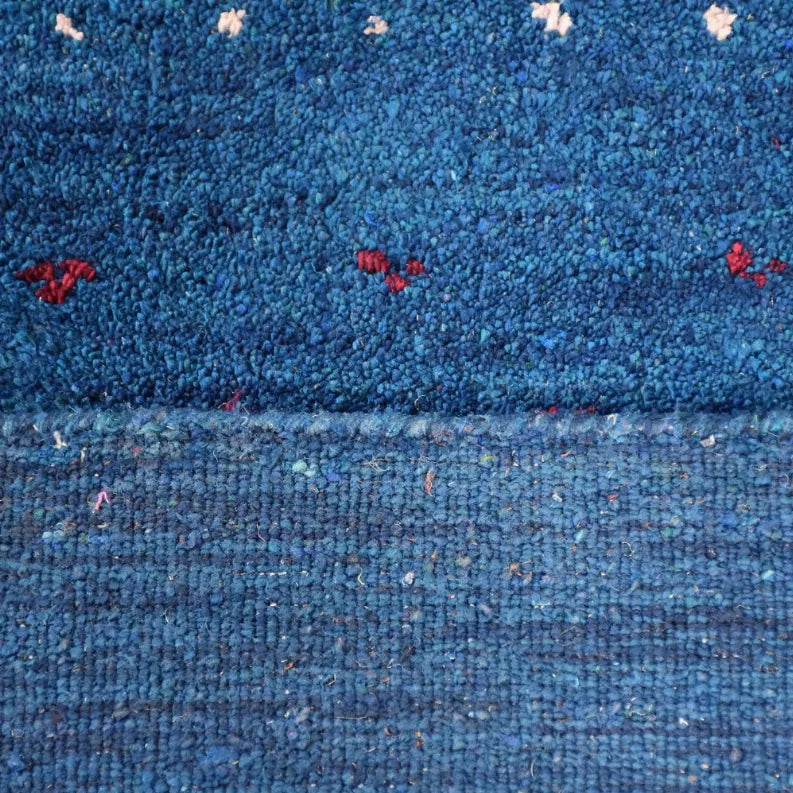 Blue hand-knotted area rug with textured pile and scattered small multicolor motifs