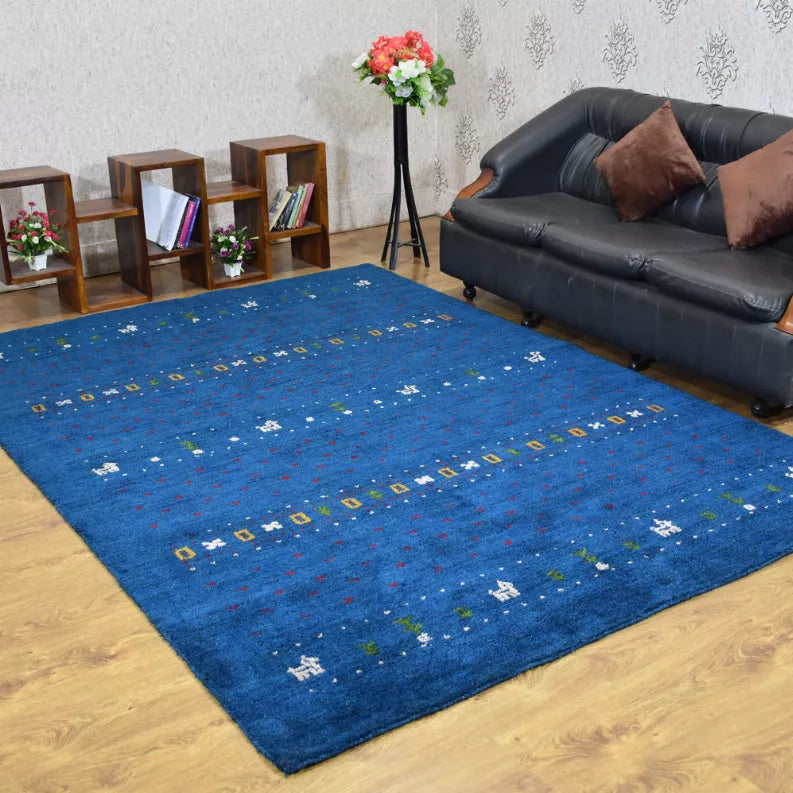Blue area rug with scattered multicolor geometric pattern on wood flooring