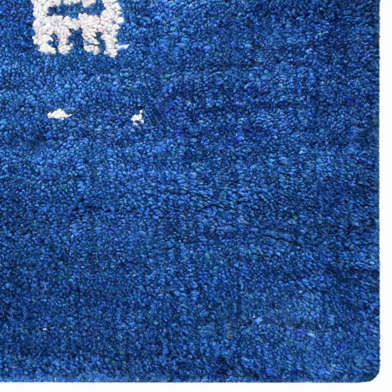 Blue hand-knotted rug close-up showing short pile texture and white motif details