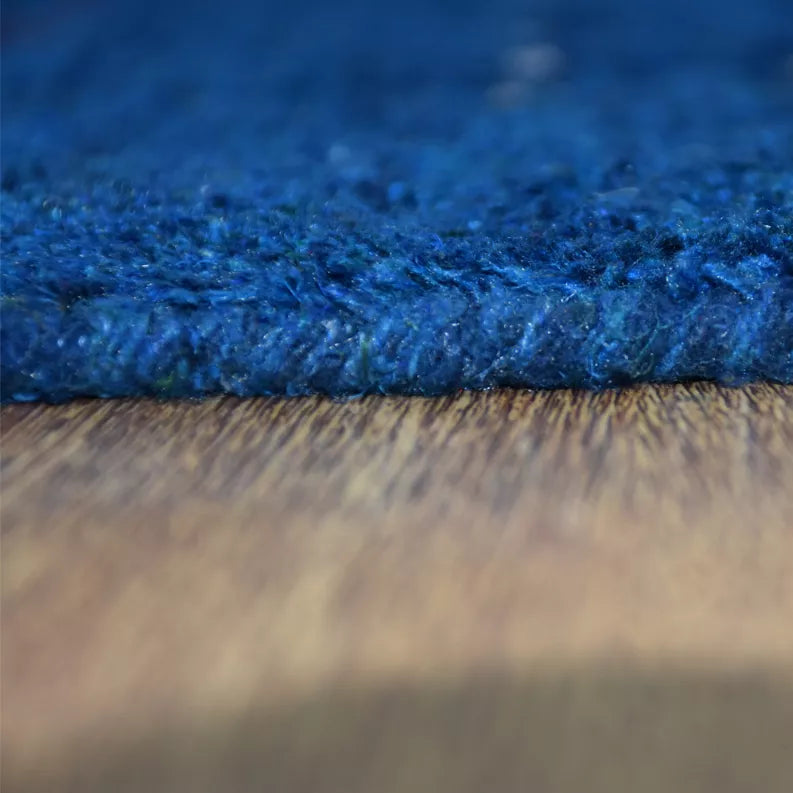Blue rug border close-up with tufted edge and dense, textured pile